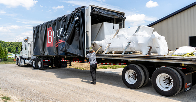 Covered Conestoga flatbed trailer transporting weather sensitive commercial freight.