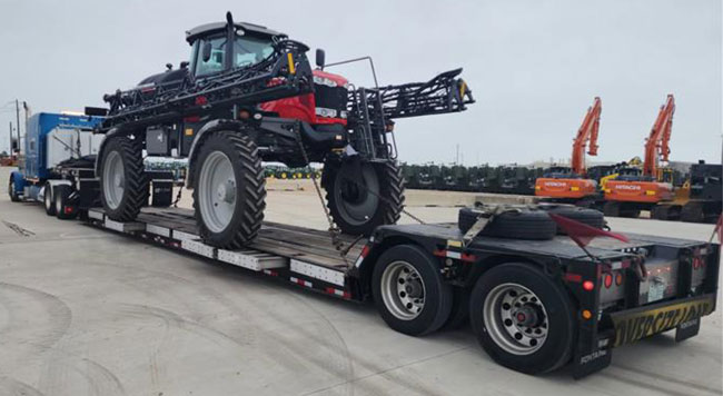 Buchanan hauling agricultural equipment with a double-drop flatbed trailer