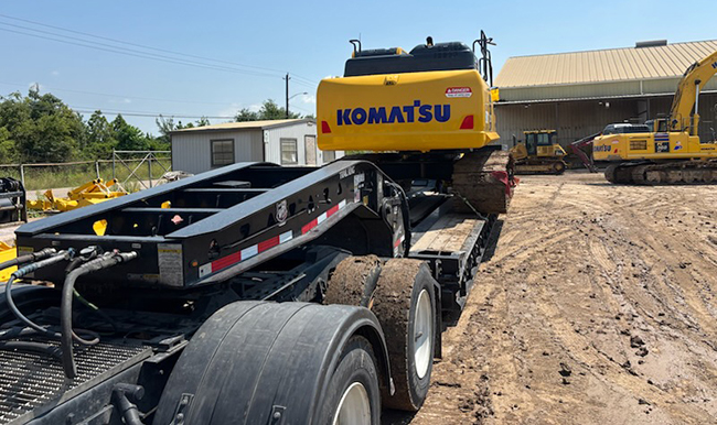 Heavy haul lowboy trailer transporting large construction machinery.