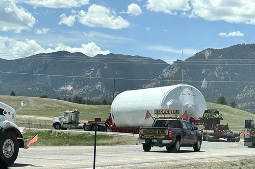 Oversized load transport with escort vehicles traveling on interstate highway.