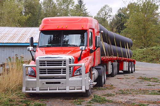 Flatbed trailer hauling construction materials to job site.