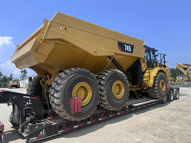 Heavy machinery transported on specialized lowboy trailer.