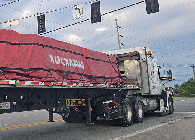 Step deck trailer hauling tall industrial machinery.