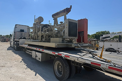 Step deck trailer hauling tall industrial machinery.