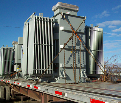 Open deck trucking transporting large industrial cargo across interstate.