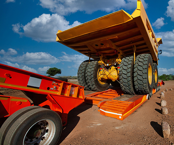 owboy trailer transporting heavy construction machinery on highway