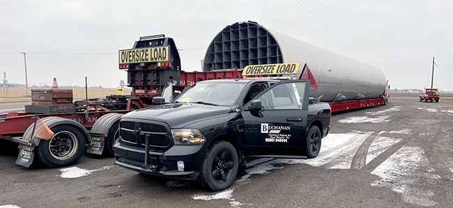 Oversized load trucking transporting large industrial equipment with escort vehicles