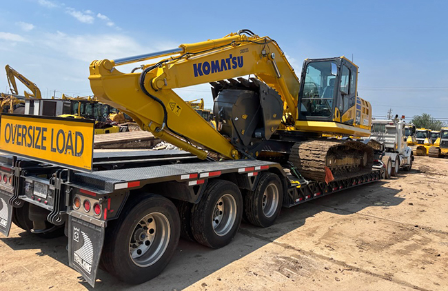 Excavator being transported on flatbed trailer for construction equipment shipping