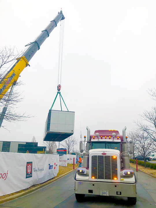 Buchanan Hauling and Rigging transports an HVAC unit on one of their stepdeck trailers to a hospital construction crew jobsite.