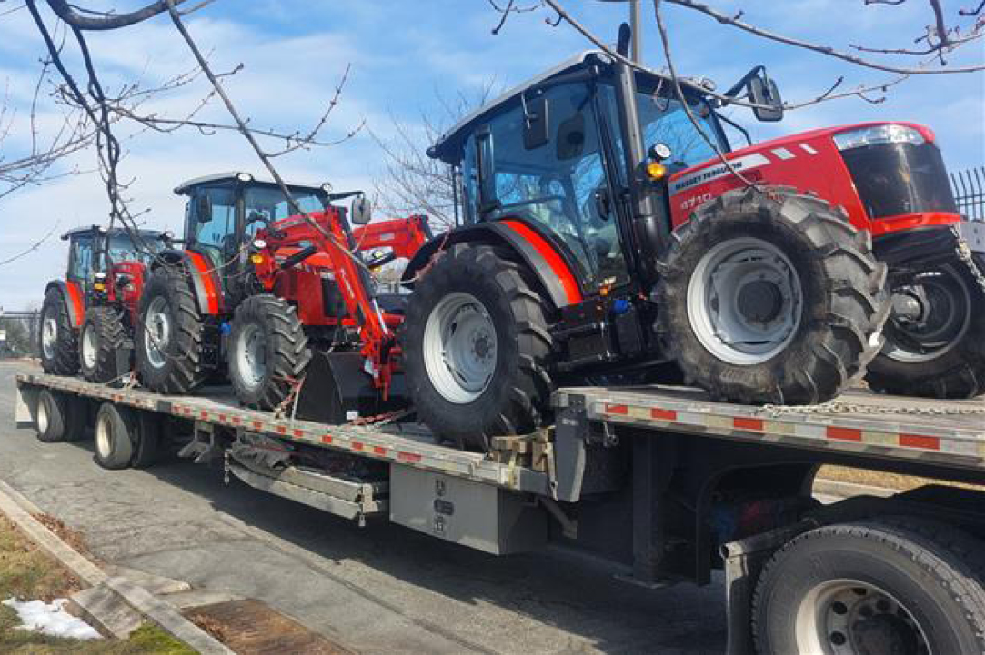 Multiple tractors loaded on a step-deck trailer by Buchanan Hauling & Rigging.