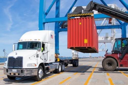 Dock container loader prepares to set a drayage container for transport on a truck carrier. Dock container loader prepares to set a drayage container for transport on a truck carrier.