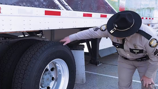 An officer reviews a semi truck trailer during a roadside inspection.