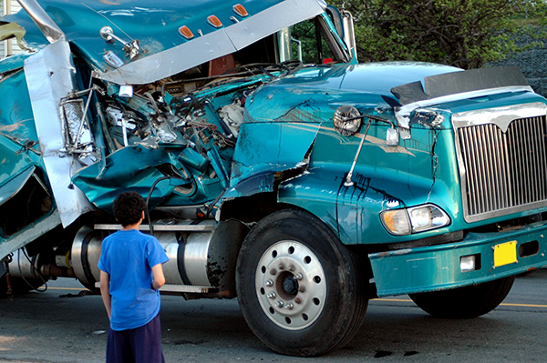 Boy looking at a semi truck with damage