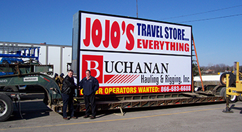 Geary Buchanan with a sign for Buchanan Hauling and Rigging, Inc. to be put up at a location Geary Buchanan with a sign for Buchanan Hauling and Rigging, Inc. to be put up at a location