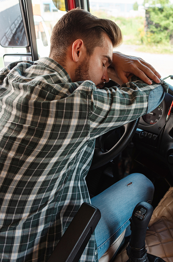 Truck driver sleeping on his steering wheel inside of his truck cab